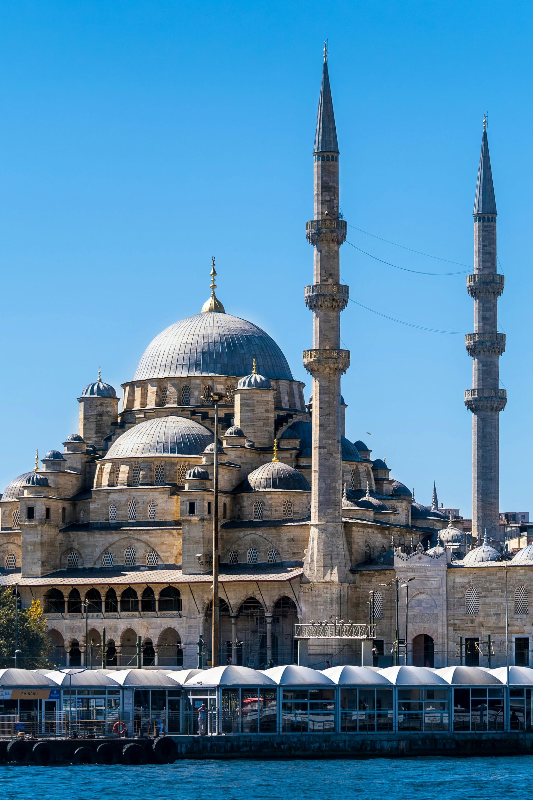 Iconic Yeni Mosque under clear sky in Istanbul, Türkiye, showcasing Ottoman architecture.